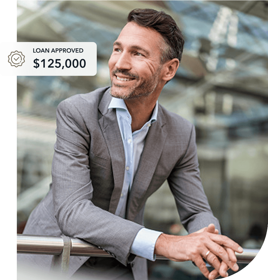 smiling business man leaning on a railing in a building