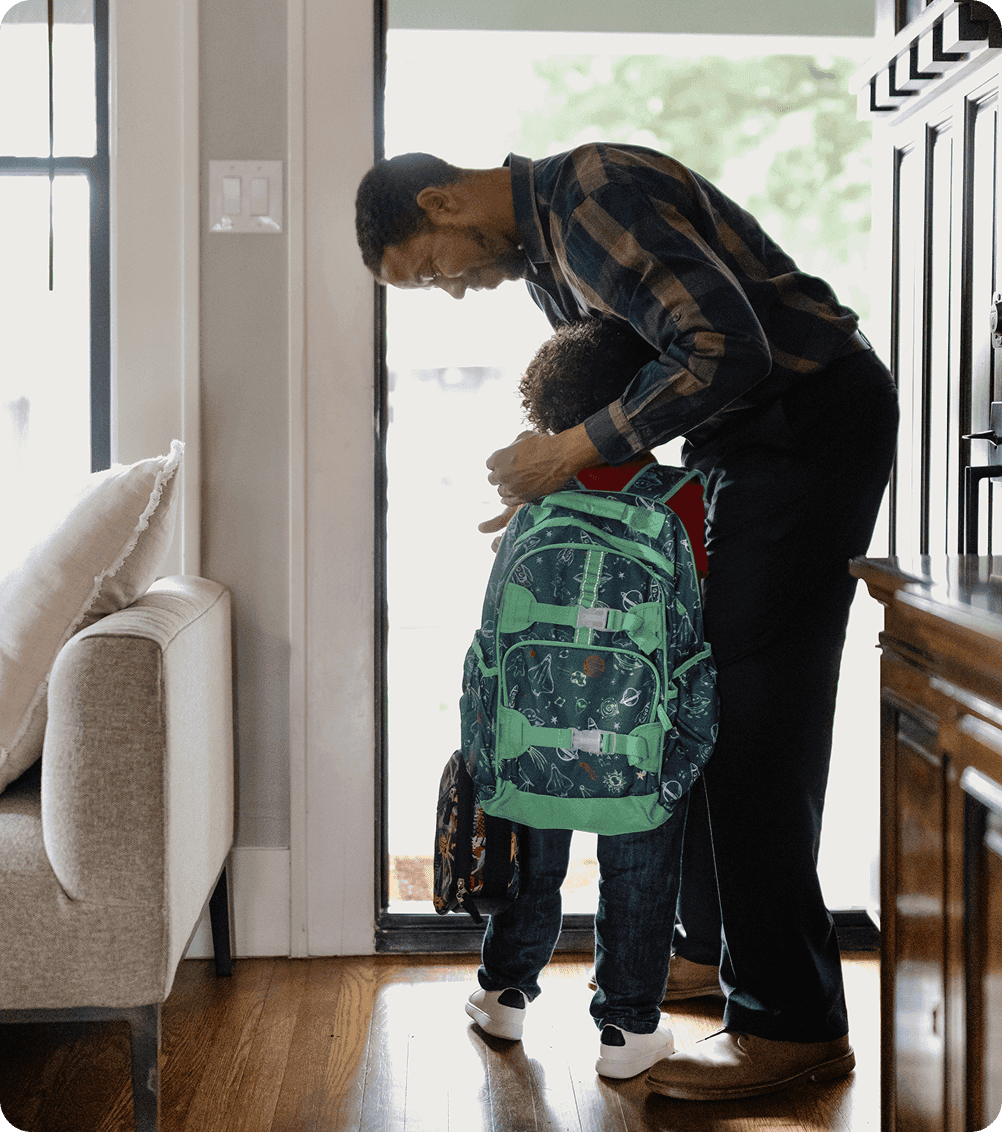 Father embracing son with school bag.  
